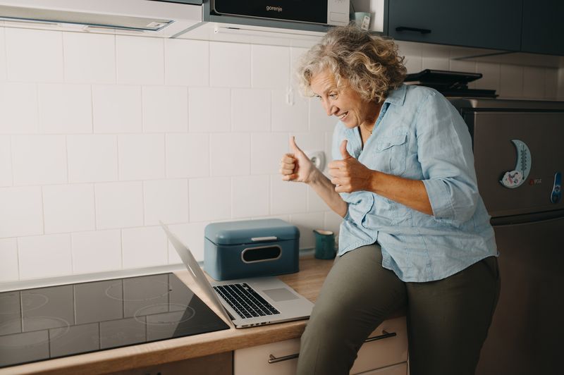 A woman celebrating in her kitchen after getting her laptop working