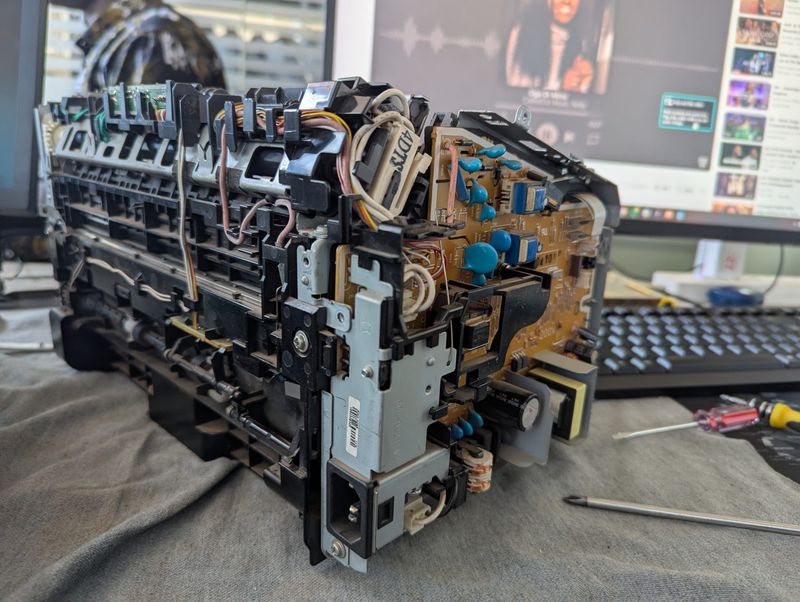 A laser printer opened up on a workbench for repair